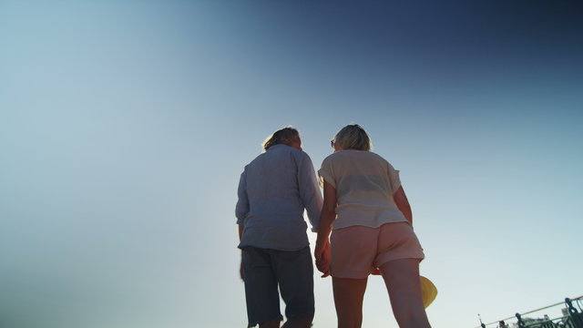 Couple on a beach holding hands walk away in slow motion 