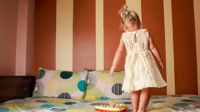 little blonde girl dances around new toy on sofa	