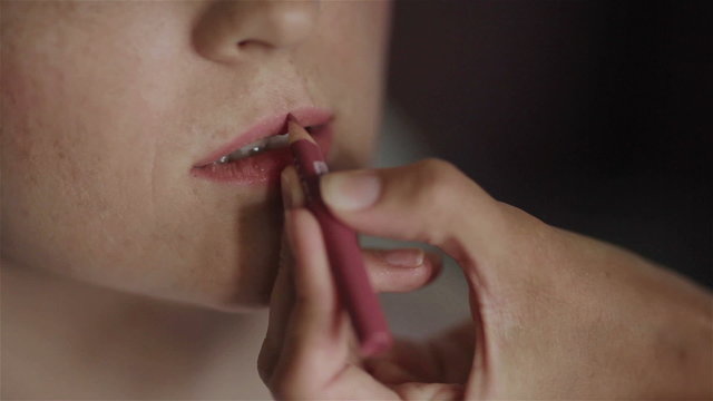 Professional make-up artist working. Applying contour to lips of model. Applying lip gloss to lips of model. Using a brush in a make-up. Using figers applying make-up. Close-up
