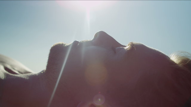 Close up of male's face laying down in the sunlight 