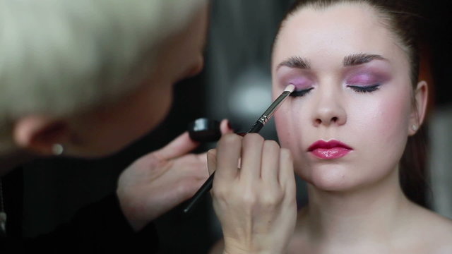 Professional make-up artist applying eyeshadow using a brush. Prepare for shooting. Close up
