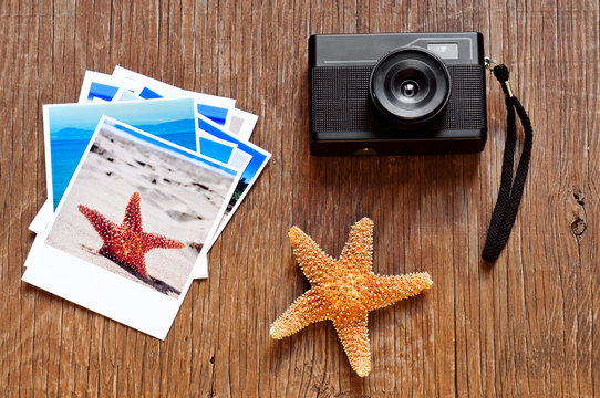 retro camera, starfish and some photos on a wooden surface