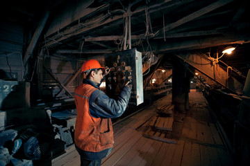 Miner worker man in a helmet at the control operator of the mine.