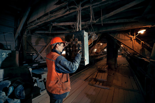 Miner worker man in a helmet at the control operator of the mine.