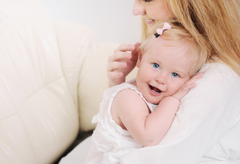 mother and her cute little baby girl having fun on the sofa