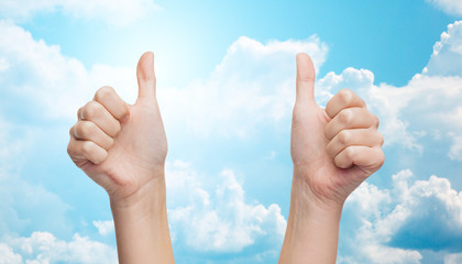 woman hands showing thumbs up over blue sky