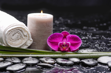 Single orchid with leaf and stones ,candle,,towel on wet background