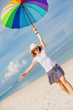Cheerful young girl with rainbow umbrella having fun on the