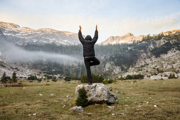 Man practicing yoga, performing a tree pose