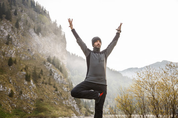 Man practicing yoga, performing a tree pose