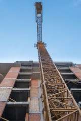 Obraz premium Yellow tower crane and concrete building construction