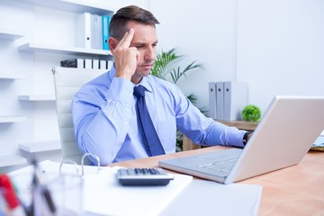 Businessman with severe headache sitting at office desk