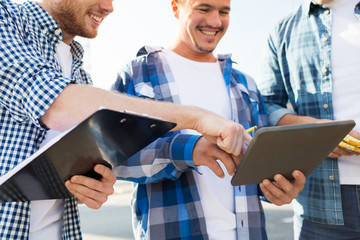 group of smiling builders with tablet pc outdoors