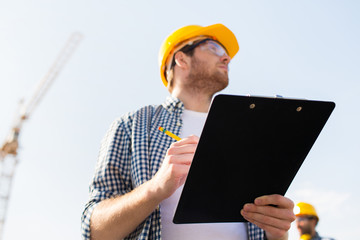 builder in hardhat with clipboard outdoors