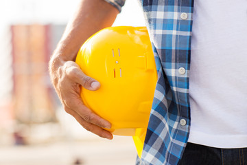 close up of builder hand holding hardhat outdoors