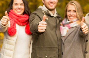 happy friends showing thumbs up in autumn park