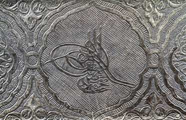 Ottoman tugra sign carved and patterned on a silver metal surface 