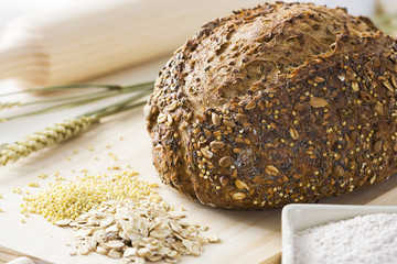 Whole grain bread on a cutting board with cereals flour and a pin