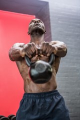 Fototapeta na wymiar Muscular man lifting a kettlebell