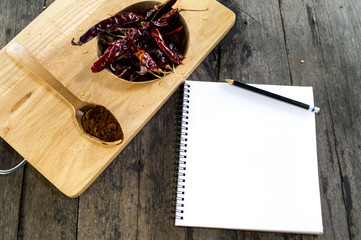 Dry Chili on wood table with notebook