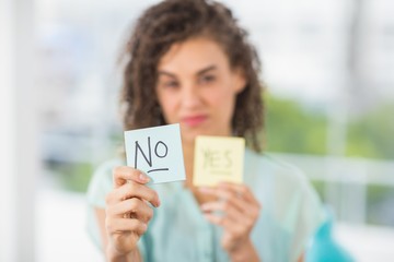 Smiling businesswoman holding yes and no sticks