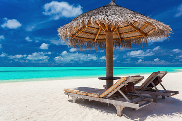 Two chairs and umbrella on a tropical beach with amazing lagoon
