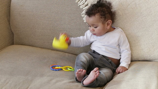 Baby boy playing with toys on a sofa