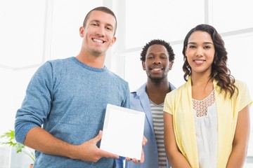 Portrait of smiling colleagues presenting tablet computer
