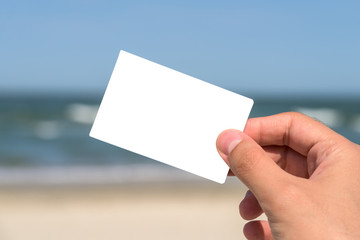 Man Hand Holding Blank White Card On Beach In Summer