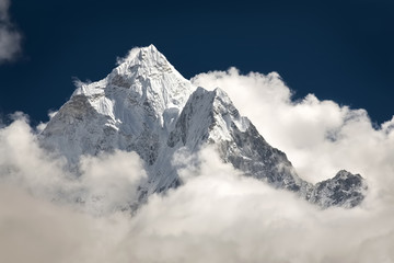 Mountain peak visible high in the sky through the clouds. - 87205200