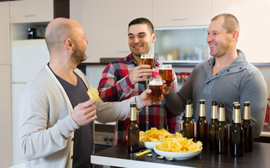 Three men with beer at kitchen