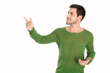 Attraktiver Mann in grün zeigt mit dem Finger auf weißen Hintergrund. 