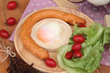 Breakfast with eggs, sausage, salad vegetables and milk.