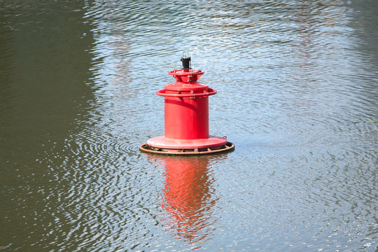 Red buoy on quiet river on summer day closeup - Powered by Adobe
