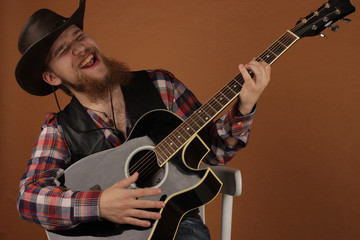 Obraz premium the young man with a red beard in a cowboy's hat sgitary in hands