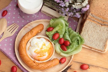 Breakfast with eggs, sausage, bread, salad vegetables and milk.