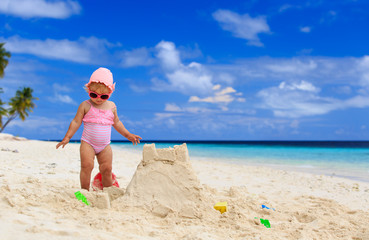 cute little girl playing with sand on the beach