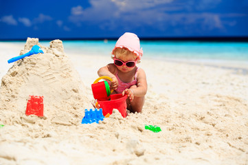 cute little girl playing with sand on the beach