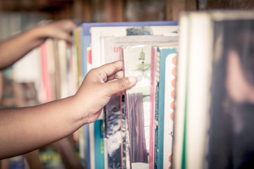hand of little girl selecting a book from book shelf in vintage