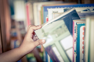 hand of little girl selecting a book from book shelf in vintage