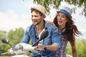 Happy young couple in love on scooter driving together.