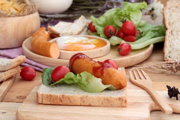 Breakfast with eggs, sausage, bread, salad vegetables and milk.