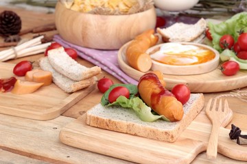 Breakfast with eggs, sausage, bread, salad vegetables and milk.
