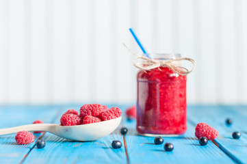 Mason jar of raspberry jam baby food on a rural white wooden