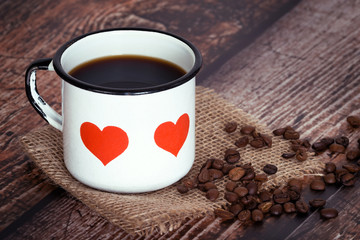 Cup of coffee in an old enamel mug on rustic background