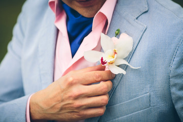 a groom's hand arranging boutonniere