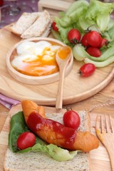 Breakfast with eggs, sausage, bread, salad vegetables and milk.