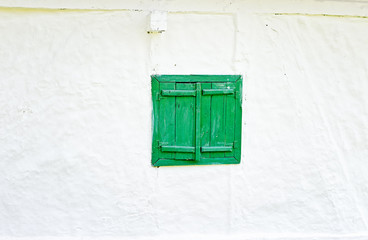 Closed green wooden window shutters on an old whitewashed wall. © Ana-Maria Tegzes