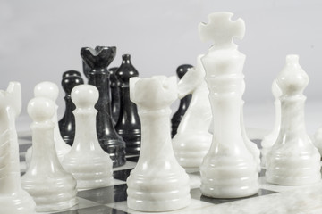 White king threatened in a chess game. Queen's Gambit. Marble pieces and chessboard