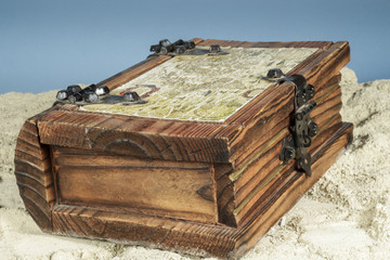 A wooden jewelry box found on a white sand beach